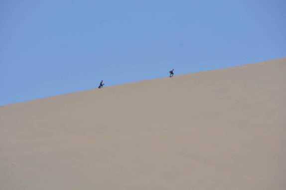 Turistas caminham em duna de Huacachina, no Peru